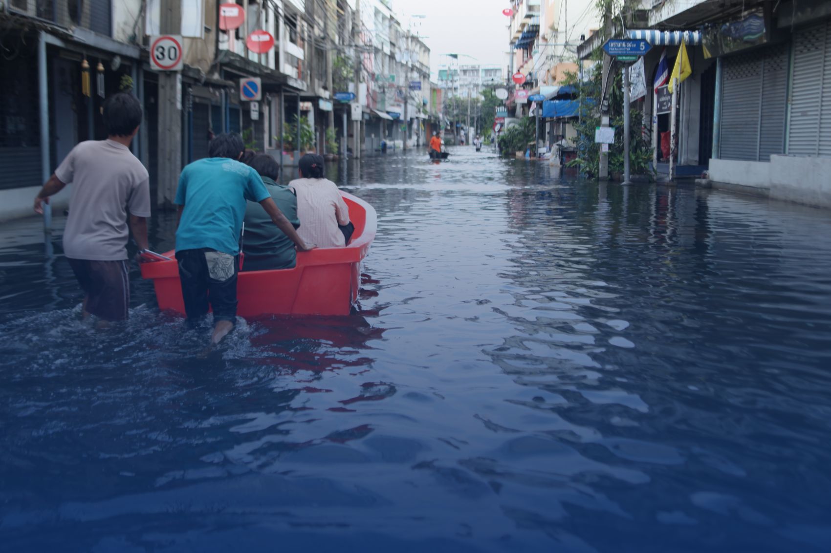 Enfants sur un bateau dans une rue inondée d'un pays du Sud qui affronte le dérèglement climatique